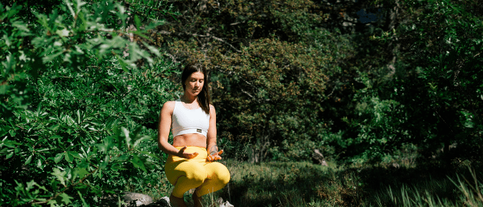 femme pratiquant de la méditation pleine conscience près d'un lac